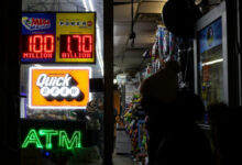 A person walks by a sign showing the $1.7 billion jackpot in the Powerball lottery drawing, in New York