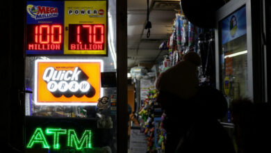 A person walks by a sign showing the $1.7 billion jackpot in the Powerball lottery drawing, in New York