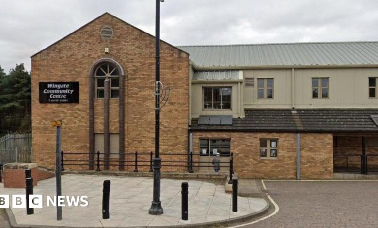 The Old Town Hall which is a red brick building with a clock tower on the left on top of a one storey extension. The main building on the right is a rectangular building with three storeys. It looks run down with the windows boarded up.