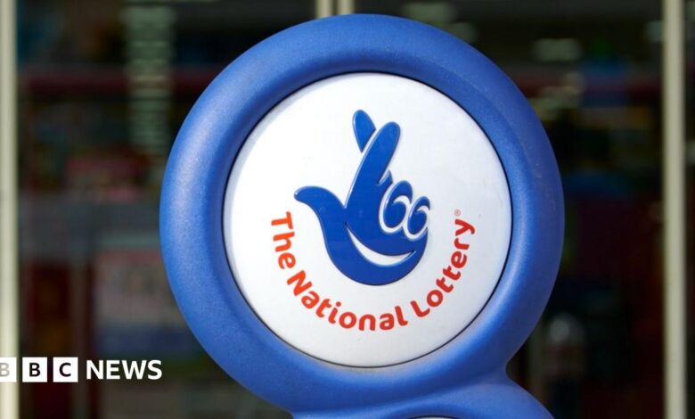A photograph of the National Lottery logo displayed outside a shop