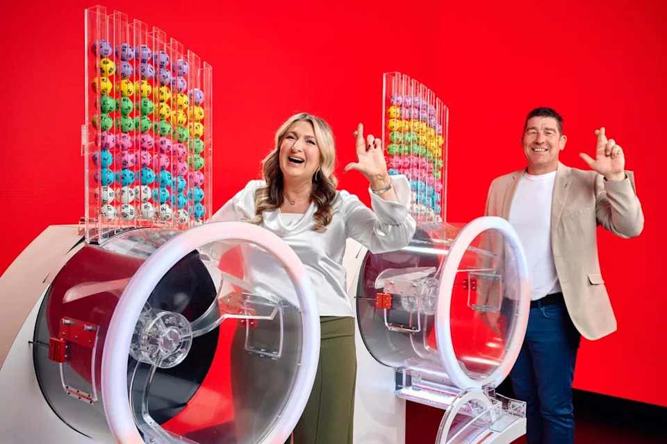 Chris and Geraldine Bradley, who won £3.57M on Lotto in 2006, alongside the two Lotto draw machines to mark the new two-round format (PA)
