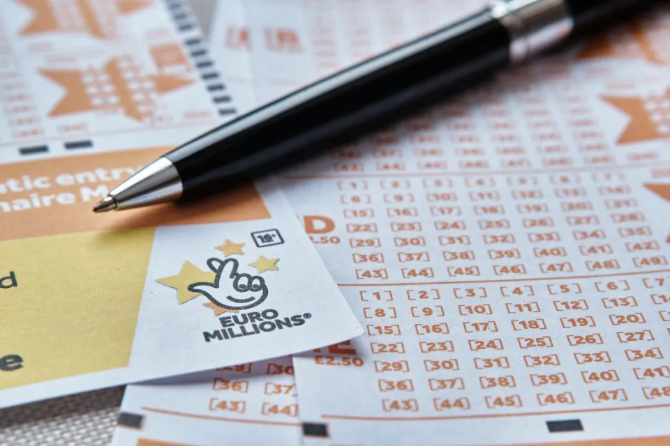 EuroMillions lottery cards and a pen.