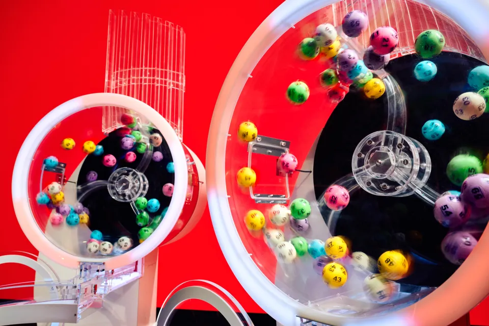 Two Lotto draw machines with colorful numbered balls in motion, ready for the new two-round format.