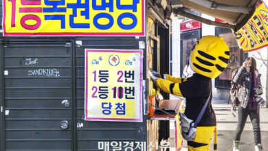 A part-timer wearing a doll mask is buying lottery restoration in Myeong-dong, Seoul. [Reporter Lee Choongwoo]