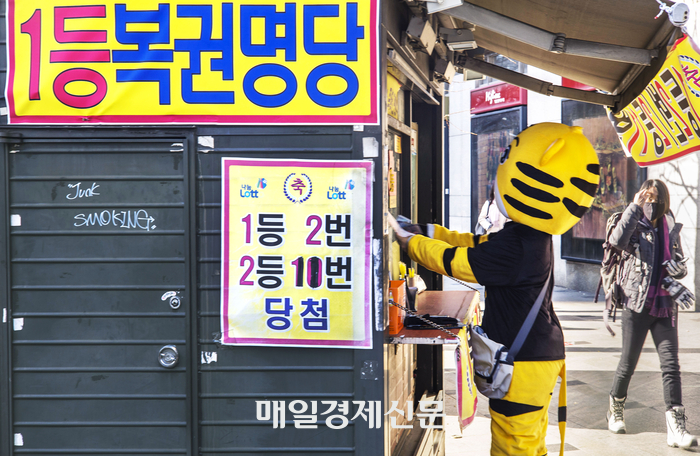 A part-timer wearing a doll mask is buying lottery restoration in Myeong-dong, Seoul. [Reporter Lee Choongwoo]