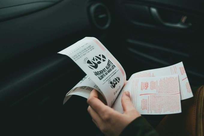 A person holds a stack of lottery papers. Photo from Pexels