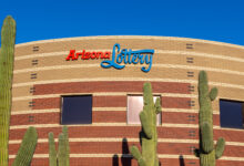 a building with the arizona lottery logo on it, with saguaro cacti in front