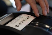 A convenience store employee grabs a Powerball lottery ticket for a customer on Monday, Dec. 22, 2025, in Portland, Ore. (AP Photo/Jenny Kane)