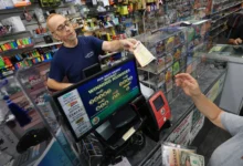 MIAMI, FLORIDA - AUGUST 26:  Robert Hadad sells Powerball lottery tickets to a customer at his Downtown Miami Souvenirs store on August 26, 2025 in Miami, Florida. The Powerball jackpot has climbed to $815 million ahead of Wednesday's drawing, making the jackpot the 10th-largest in Powerball history. (Photo by Joe Raedle/Getty Images)