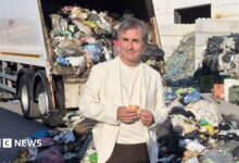 Roberto Nicola Toscano standing in front of a heap of trash. There is a garbage truck in the background