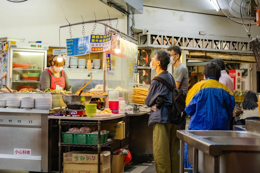 Customers line up at a counter of a food outlet.