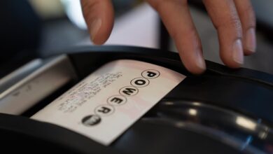 A convenience store employee grabs a Powerball lottery ticket for a customer in December 2025, in Portland, Ore.